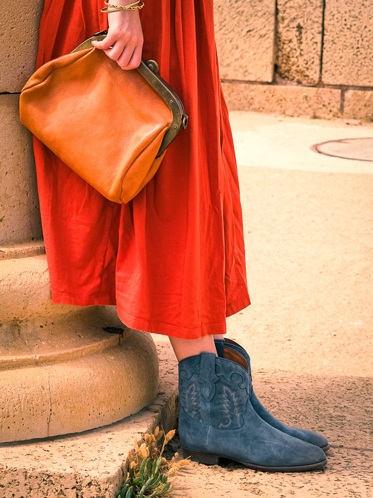 Jeune femmes portant Shiloh Heritage, Bottines Early Midnight, santiag en daim, couleur Denim, fabrication artisanal, cuir d’Italie, short soie jaune. Young woman wearing Shiloh Heritage, Early Midnight boots, Western boots in suede, color Denim, handcrafted,leather from Italy, silk yellow short